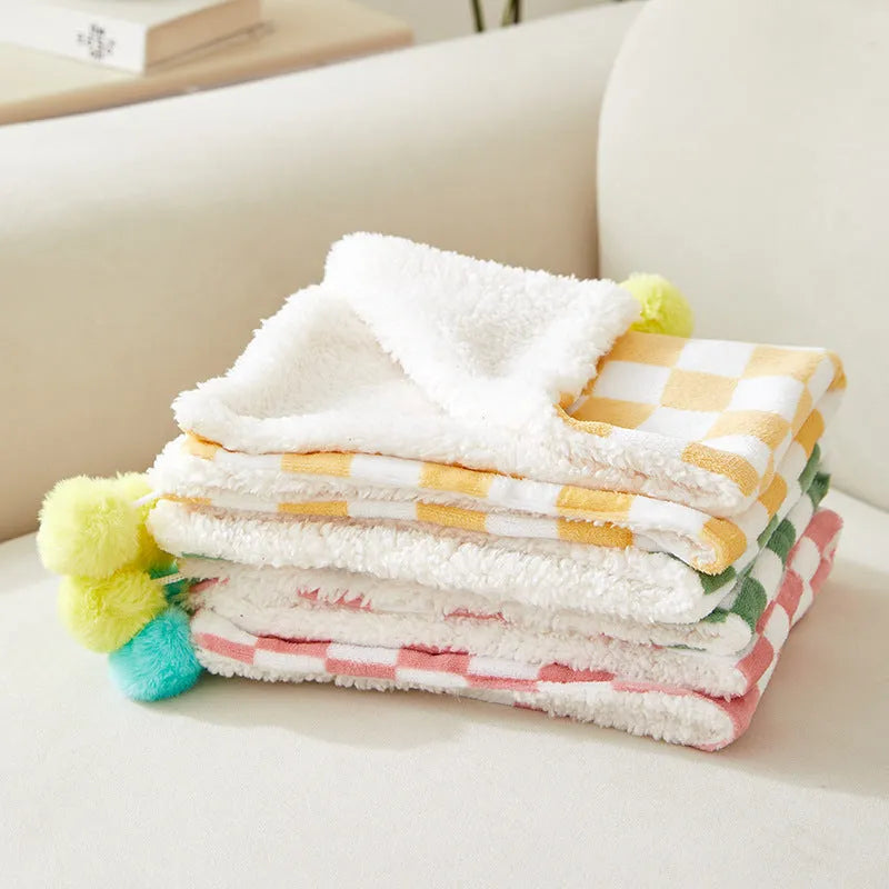Green plaid pattern pet blanket with soft fleece texture on sofa