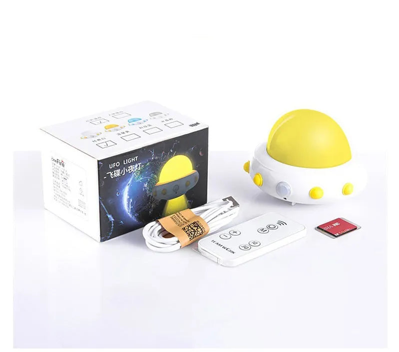 Remote control UFO shaped bedside night light in blue, pink, or white on a bedside table.