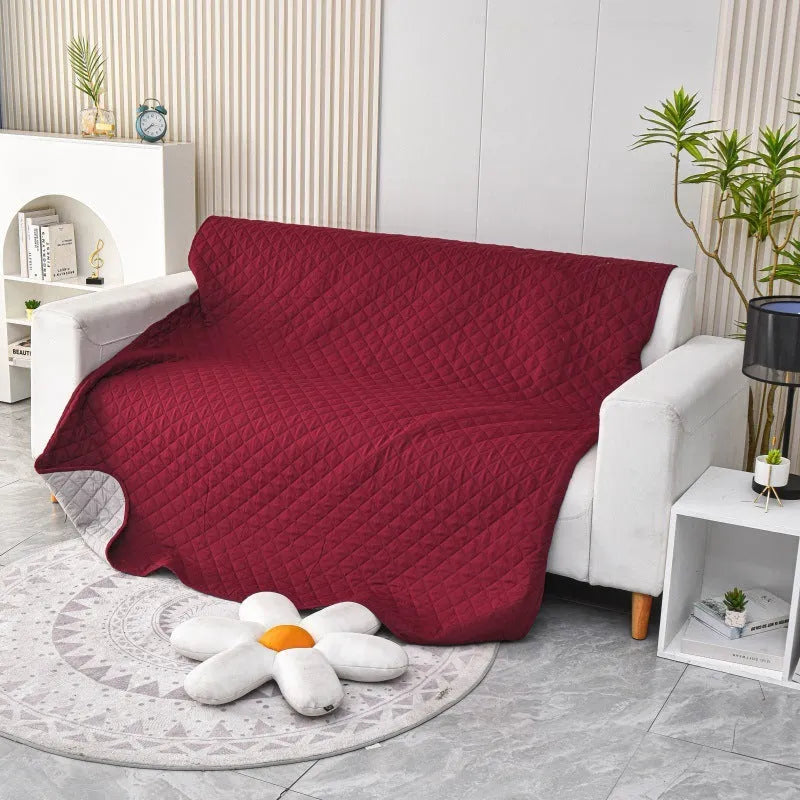 Reversible dog blanket showing two colours, laid flat on a sofa as a protective cover