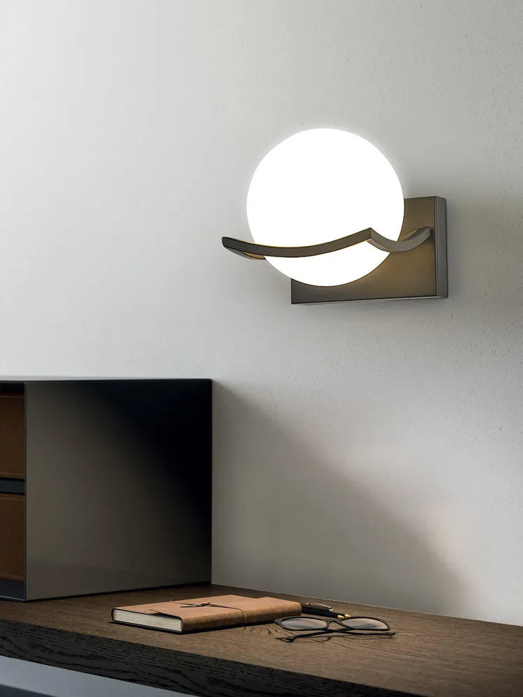 Modern minimalist black wall lamp with striped clear cover mounted beside a bed