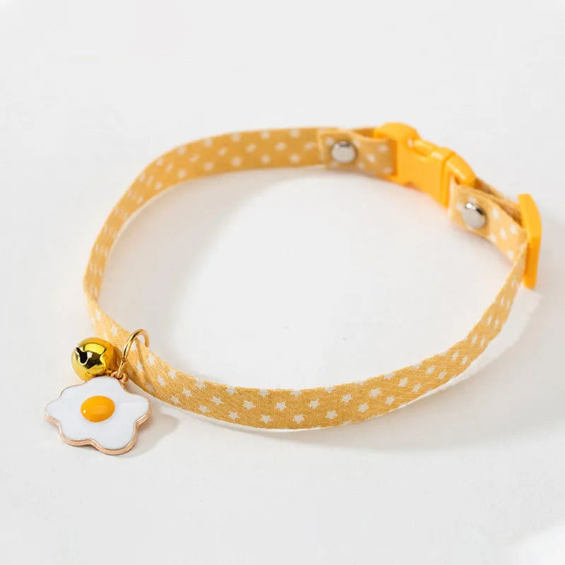 Green adjustable cat collar with a metal bell and pink bow tie on a small dog