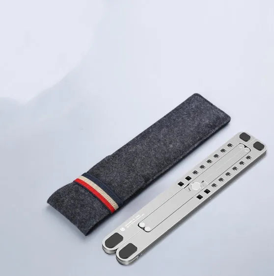 A folded silver aluminium laptop stand next to an open laptop, showing its thin profile and adjustable angle mechanism.