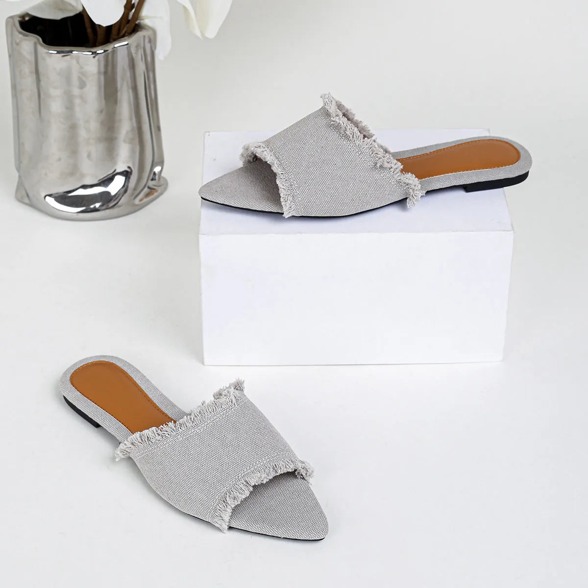 Women's denim flat slippers with a tassel, shown in available colours like apricot, black, and wine red.