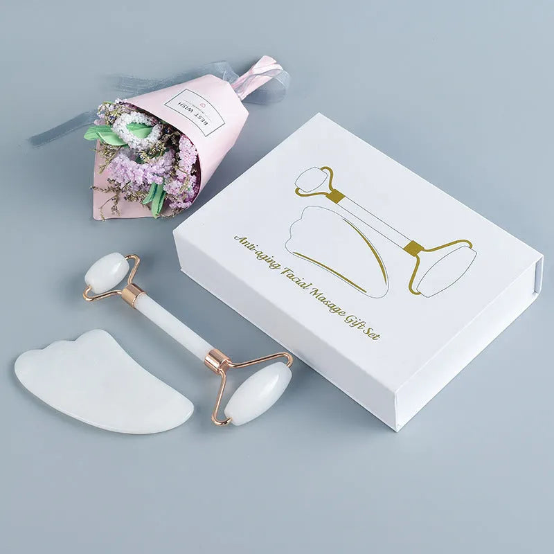 White jade double-headed facial roller and scraping board set on a plain surface.