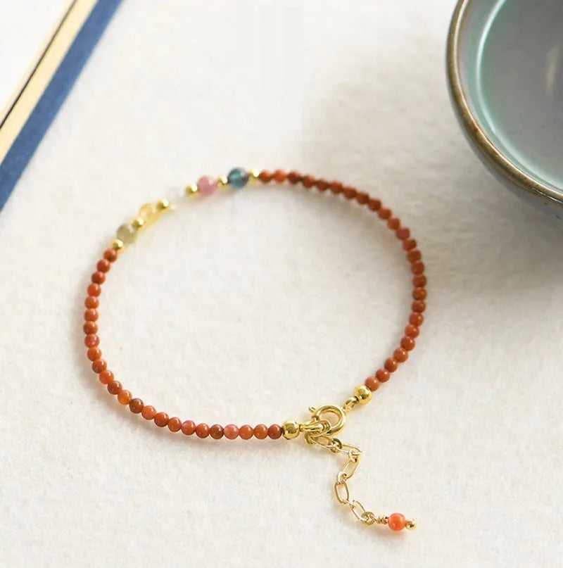 Women's geometric braided rope bracelet with freshwater pearls, amethyst, pomegranate, and red beads.