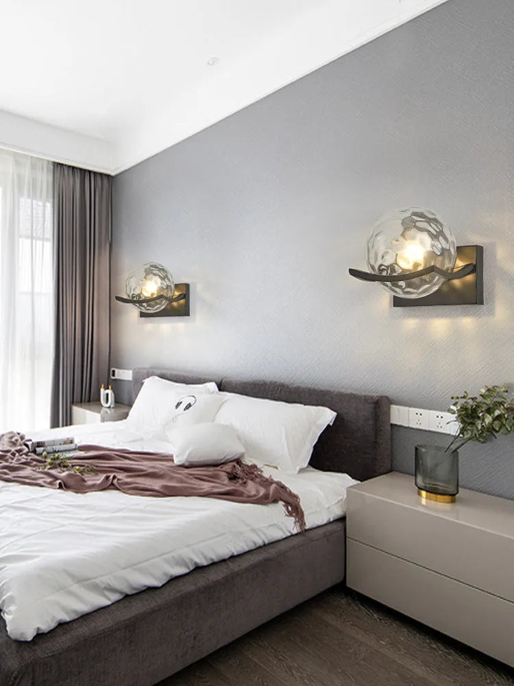 Modern minimalist black wall lamp with striped clear cover mounted beside a bed