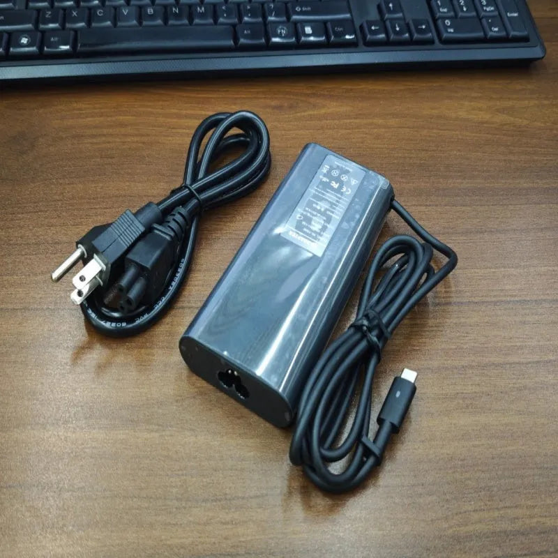 Black 65W Type-C laptop power adapter with a set of interchangeable international plug heads.