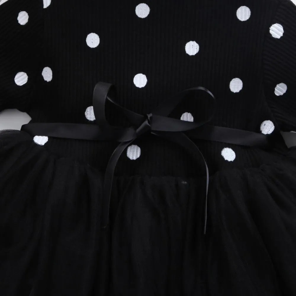 Baby girl wearing a long sleeve black lace tutu dress for a christening or birthday party.