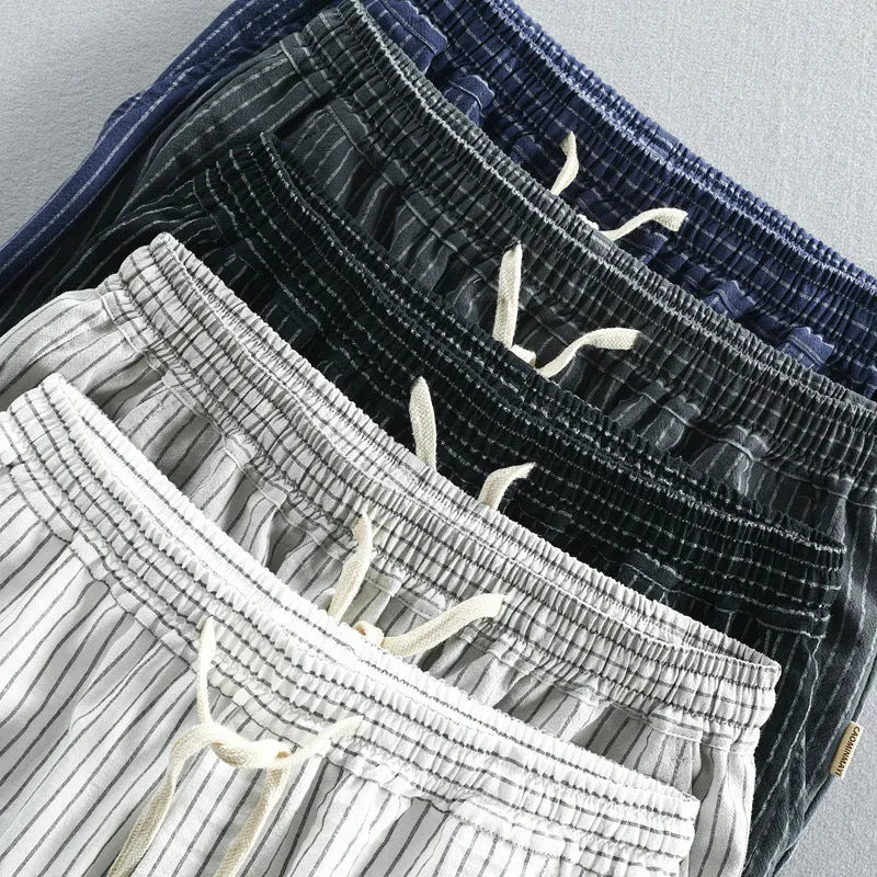 Man wearing striped light blue cotton casual shorts with a mid waist and loose straight fit.
