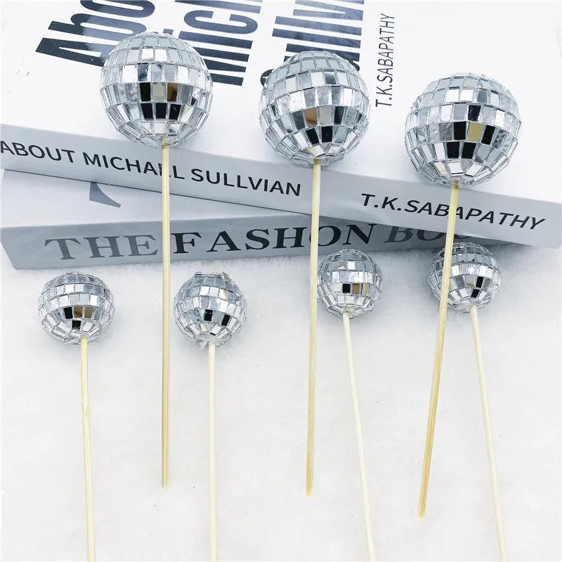 Glass disco ball cake decorations with wooden sticks in multiple sizes on birthday cake