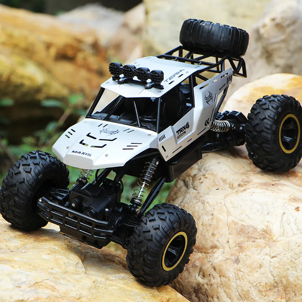Large black or silver 4WD remote control climbing car on off-road terrain with wireless remote.