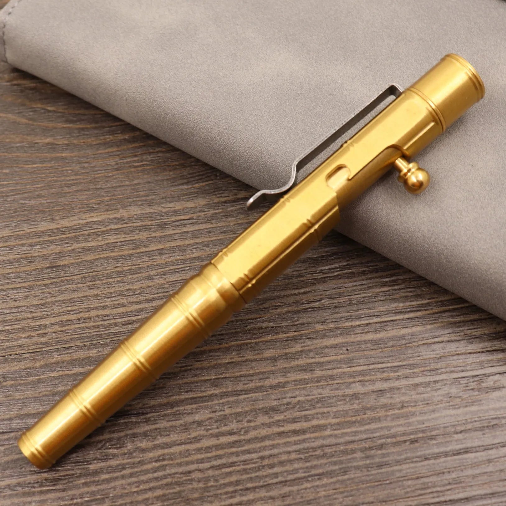 Brass bolt-action tactical pen in a retro copper finish, showing press mechanism and textured barrel.