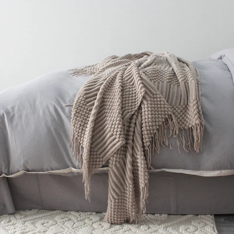 Small grey polyester nap blanket folded on a sofa, showing its texture and size.