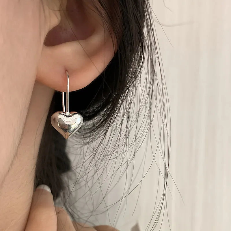 Silver-coloured heart-shaped earrings with three-dimensional glossy design and Korean style aesthetics