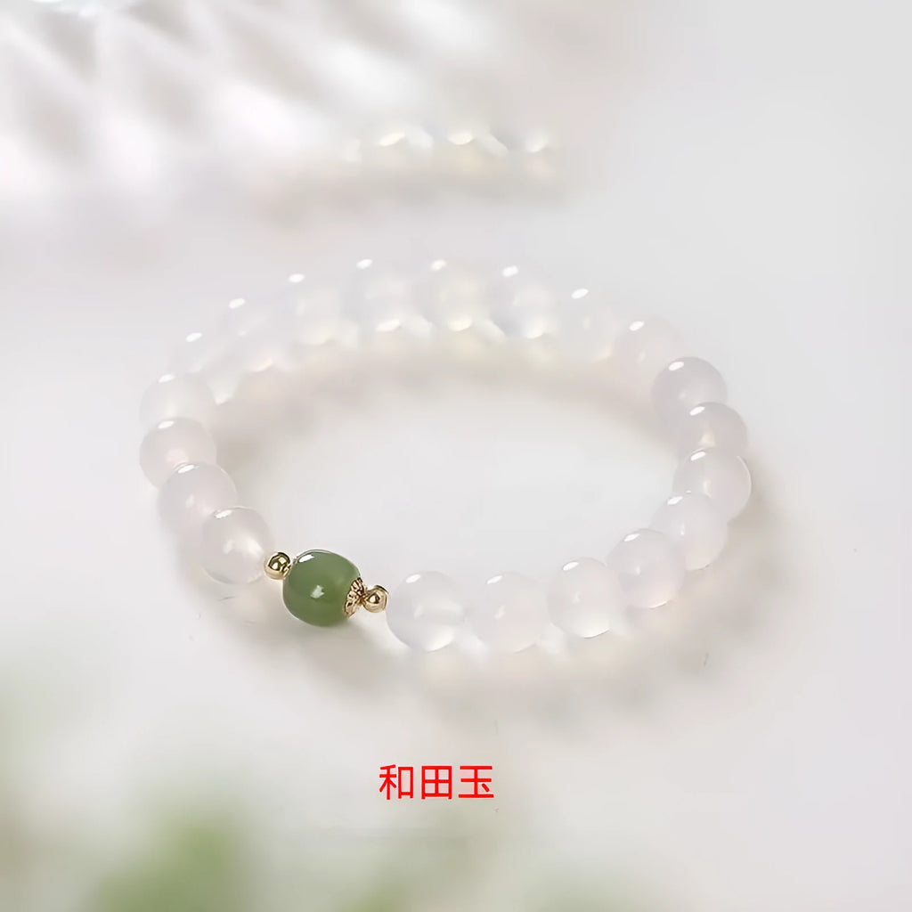 Handmade white agate and crystal bracelet with red cinnabar inlay on a wrist.