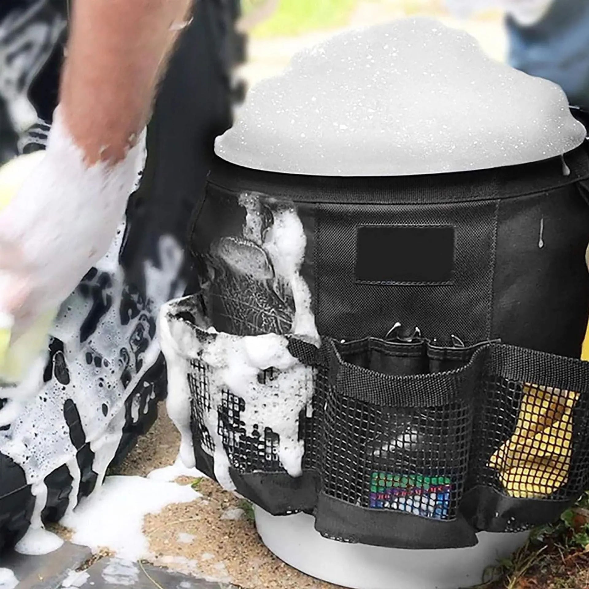 Black cylindrical polyester storage bag hanging on a 5-gallon barrel for outdoor tool organisation