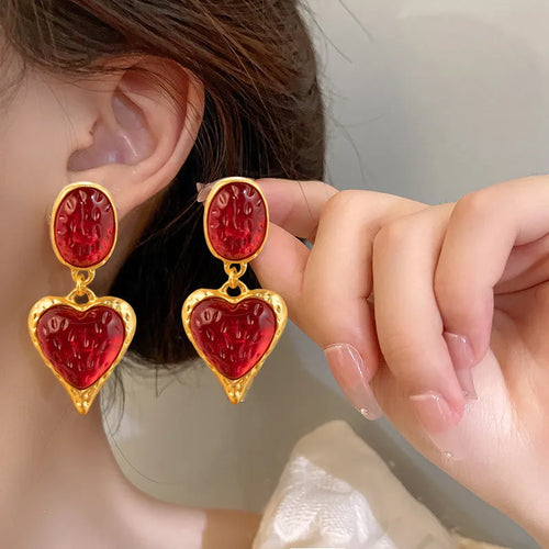 A pair of alloy silver needle pleated oval love heart stud earrings on a purple background.