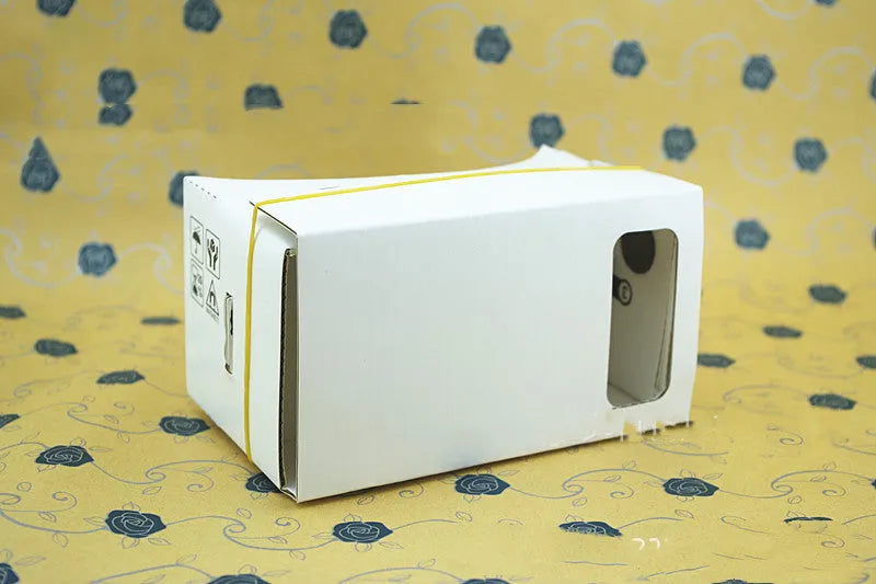 Foldable pink and white cardboard VR headset for smartphones with lenses and a head strap.