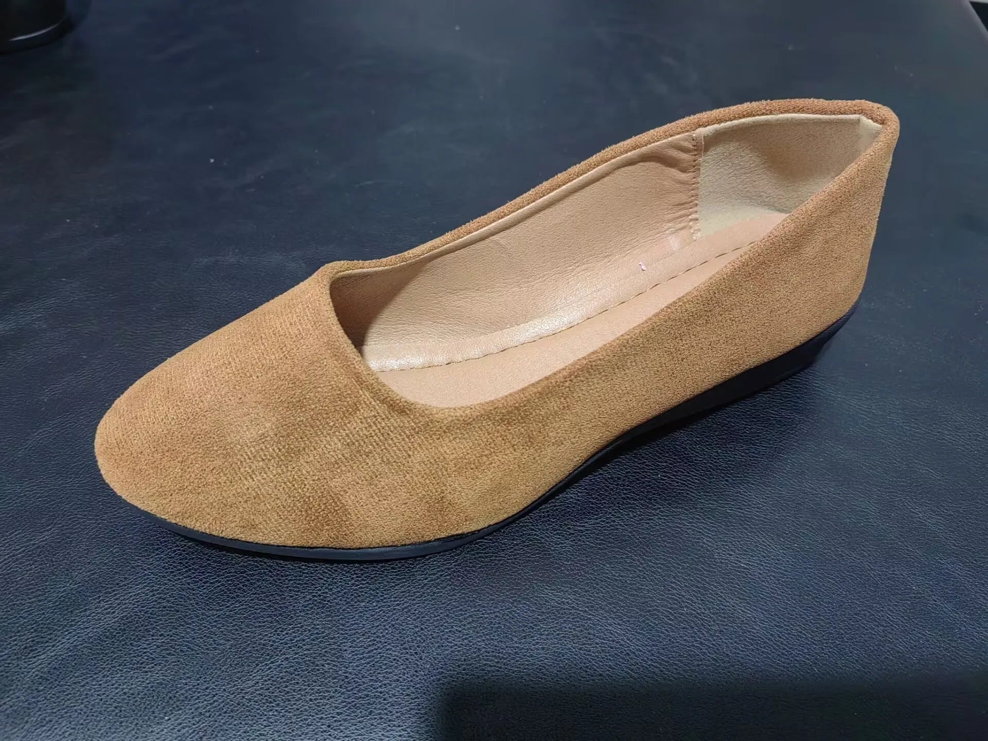 Women's black suede low wedge pumps with pointed toe and shallow mouth design on a rubber sole.