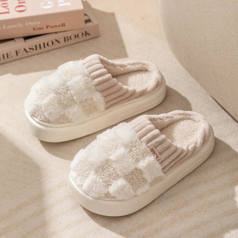 Women's plaid patterned coral velvet indoor slippers with a thick soft sole on a wooden floor.