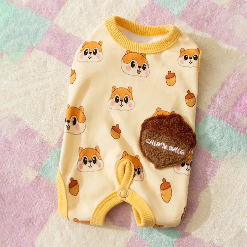 Small dog wearing Chip 'n' Dale themed cream onesie with yellow trim and embroidered acorn pocket