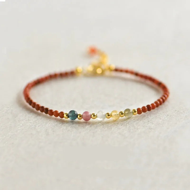 Women's geometric braided rope bracelet with freshwater pearls, amethyst, pomegranate, and red beads.