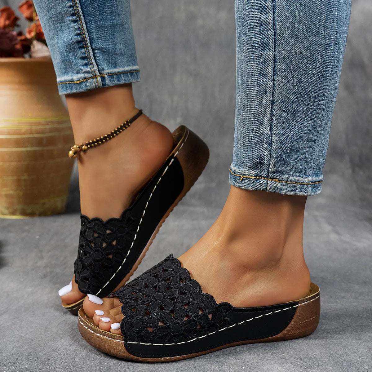 Women's black wedge beach slipper with floral cutouts and fish mouth toe shape on a rubber sole.