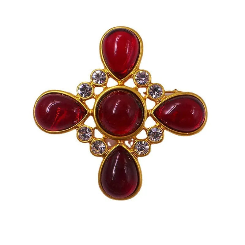 Close-up of a detailed baroque cross brooch with crystal accents on a zinc alloy base.
