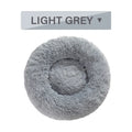 Fluffy long plush donut-shaped pet bed for dogs and cats on a wooden floor.