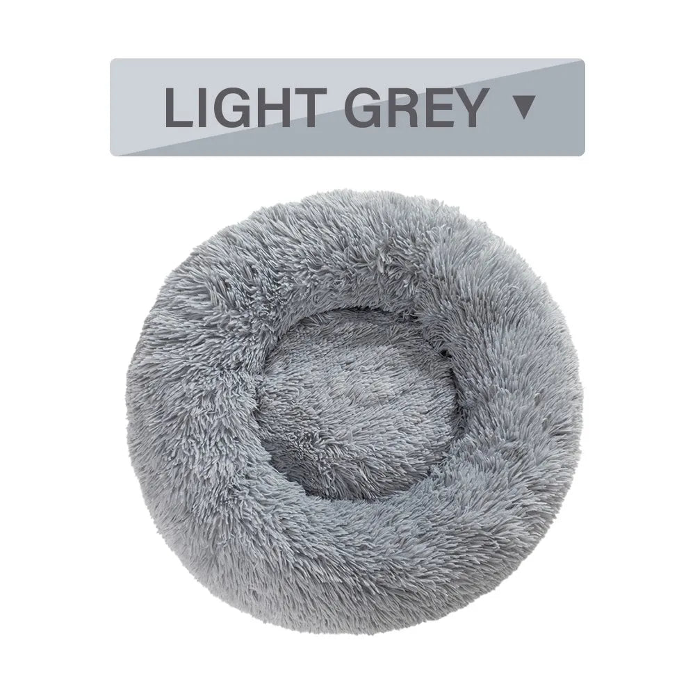 Fluffy long plush donut-shaped pet bed for dogs and cats on a wooden floor.