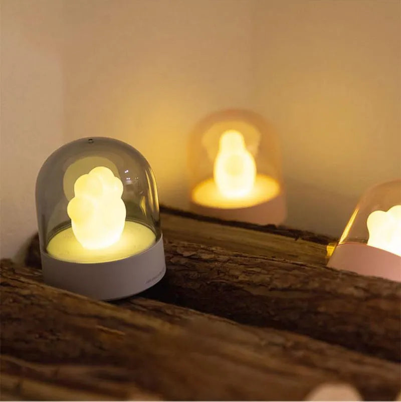 Grey or pink cat paw shaped USB rechargeable night light with musical functions on wooden desktop