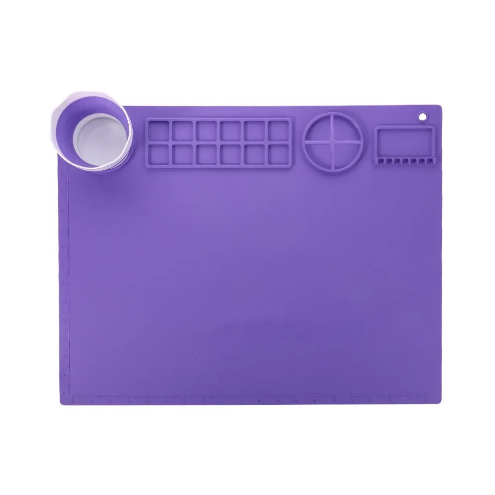 Light blue silicone painting mat with an integrated bowl on one side, positioned on a wooden table.