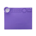 Light blue silicone painting mat with an integrated bowl on one side, positioned on a wooden table.