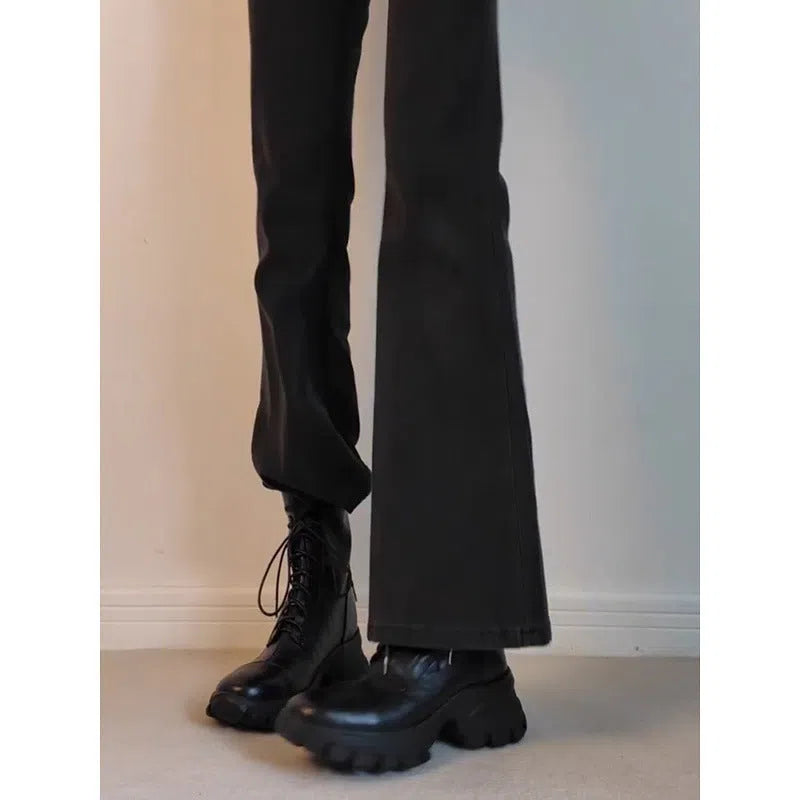 Black thick-soled motorcycle boots with back zipper and lace-up closure on a grey background