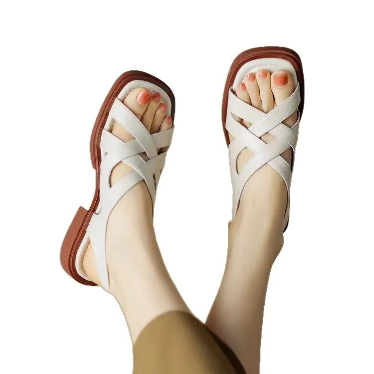 Women's glossy patent leather square toe sandals with cross strap on a brown background