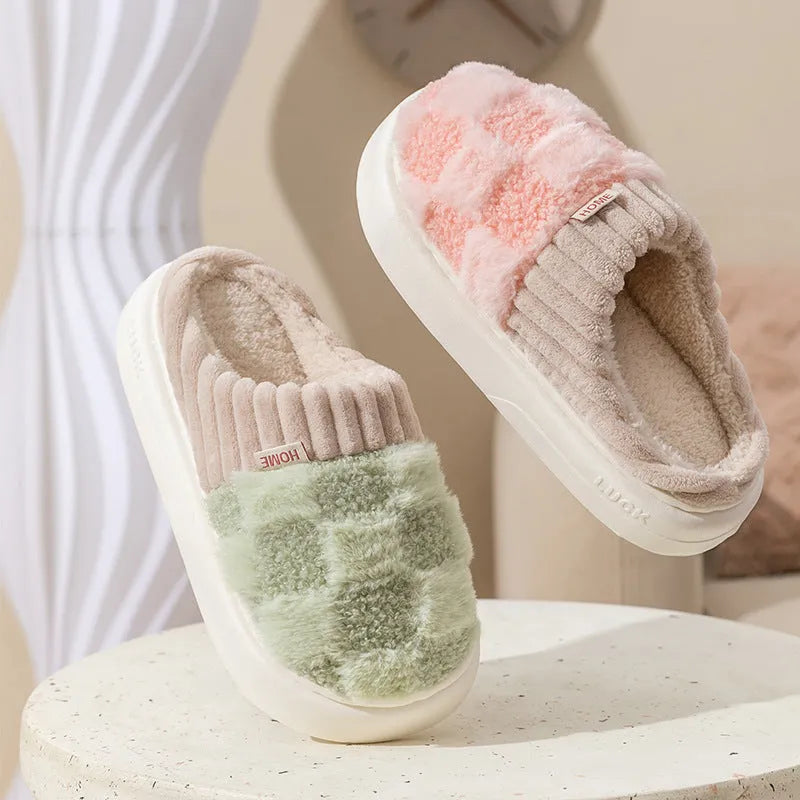Women's plaid patterned coral velvet indoor slippers with a thick soft sole on a wooden floor.