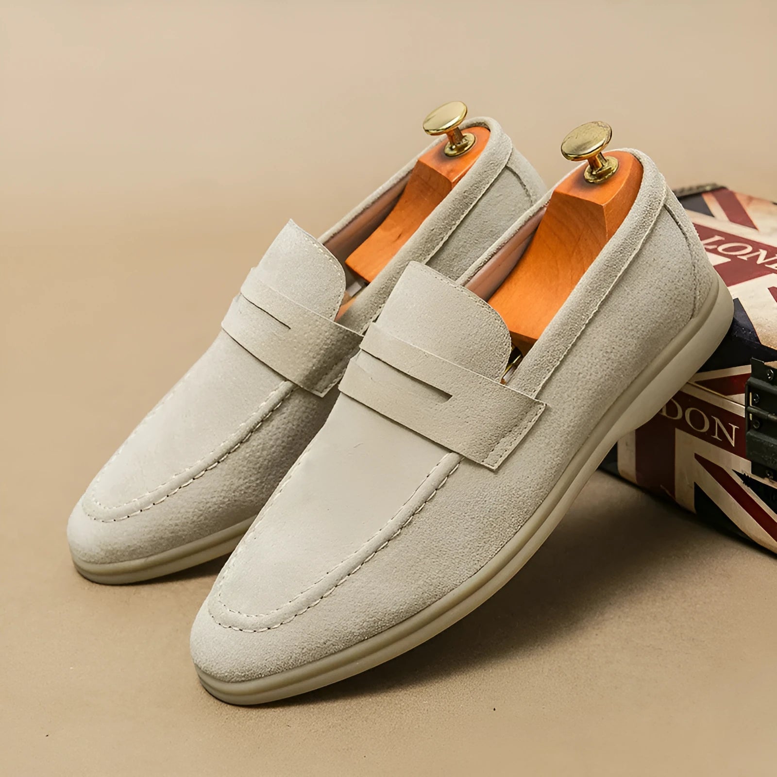 Men's brown leather slip-on casual shoes with round toe and rubber sole on a wooden floor.