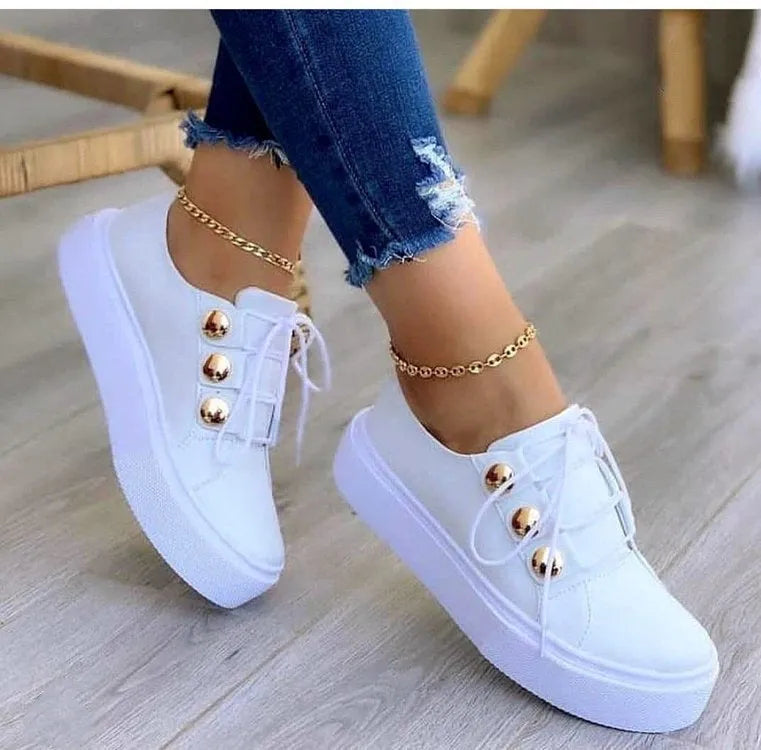 Women's white lace-up casual sneaker flats with silver rivet details on the round toe and low-top design.