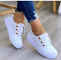 Women's white lace-up casual sneaker flats with silver rivet details on the round toe and low-top design.