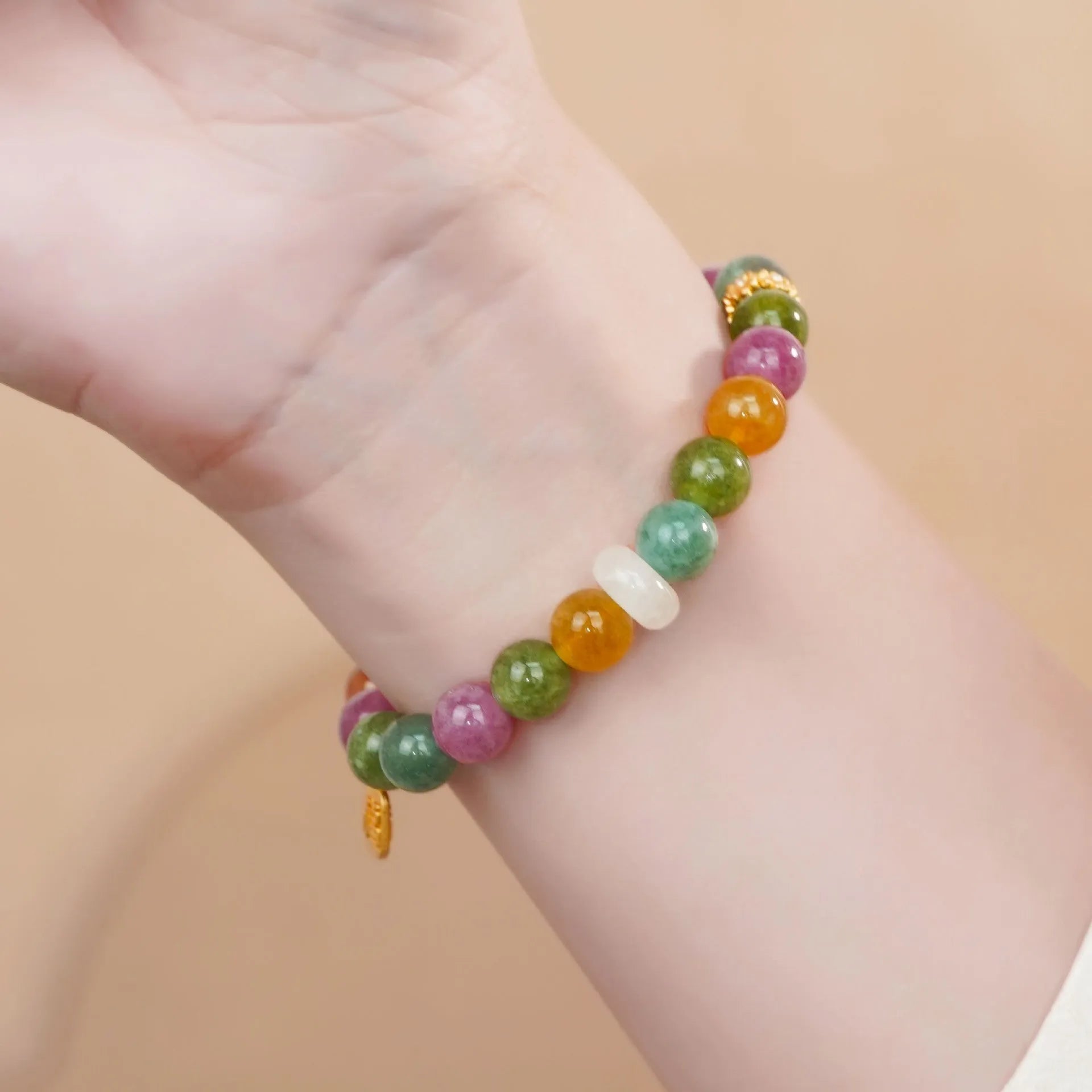 Rainbow coloured electroplated tourmaline half bracelet for women on a wrist.