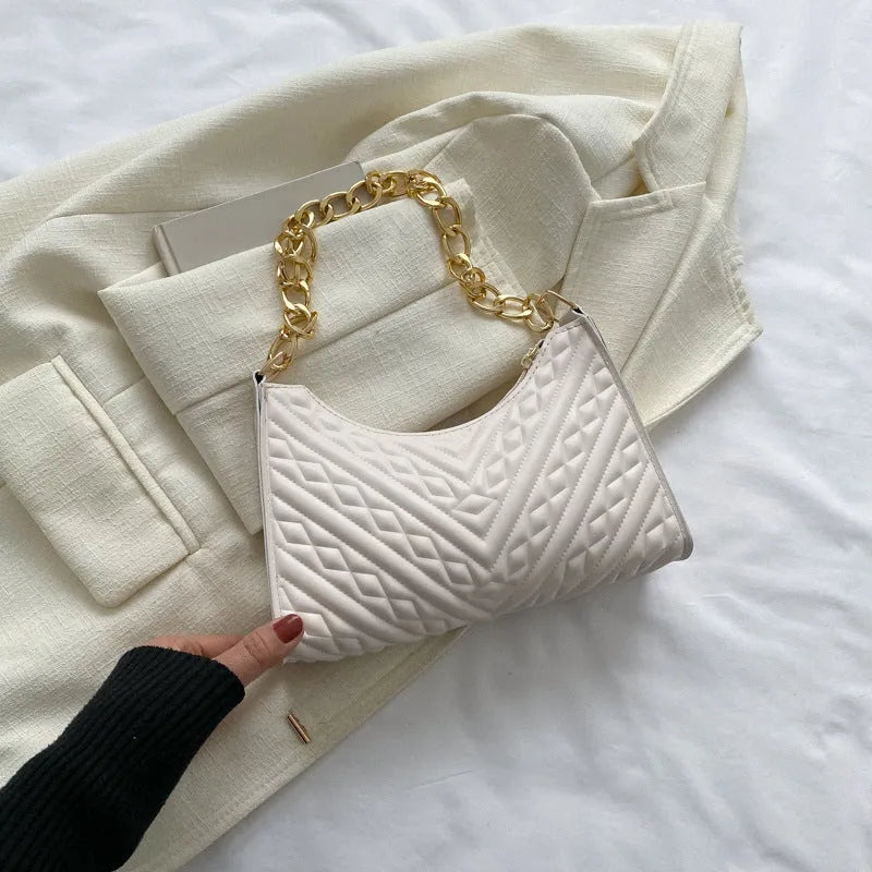 Vertical square brown PU shoulder bag with chain strap and soft handle on a table