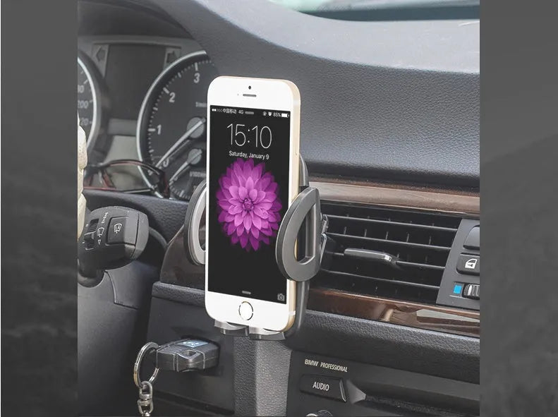 Black plastic car air vent phone holder mounted on car dashboard with mobile phone securely in cradle