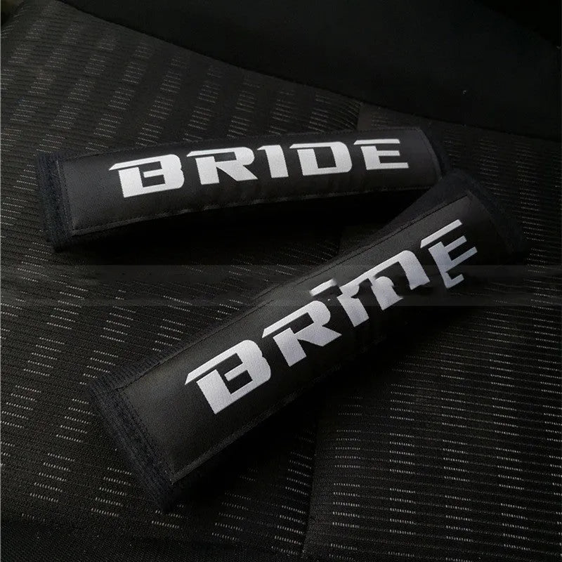 Pair of black car seat belt shoulder pads made from sponge cloth, showing embroidery detail and size.