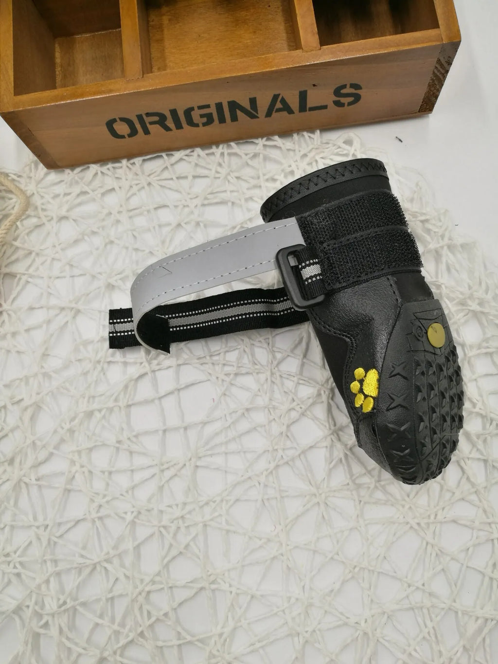 Black dog shoes with waterproof PVC sole and adjustable fuzzy belt on a dog's paw