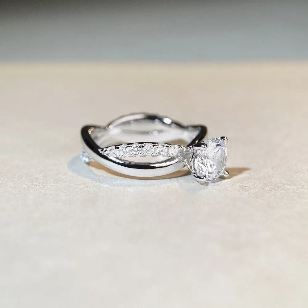 A geometric silver ring with a twisted band and a 1 carat moissanite stone in a four-claw setting.