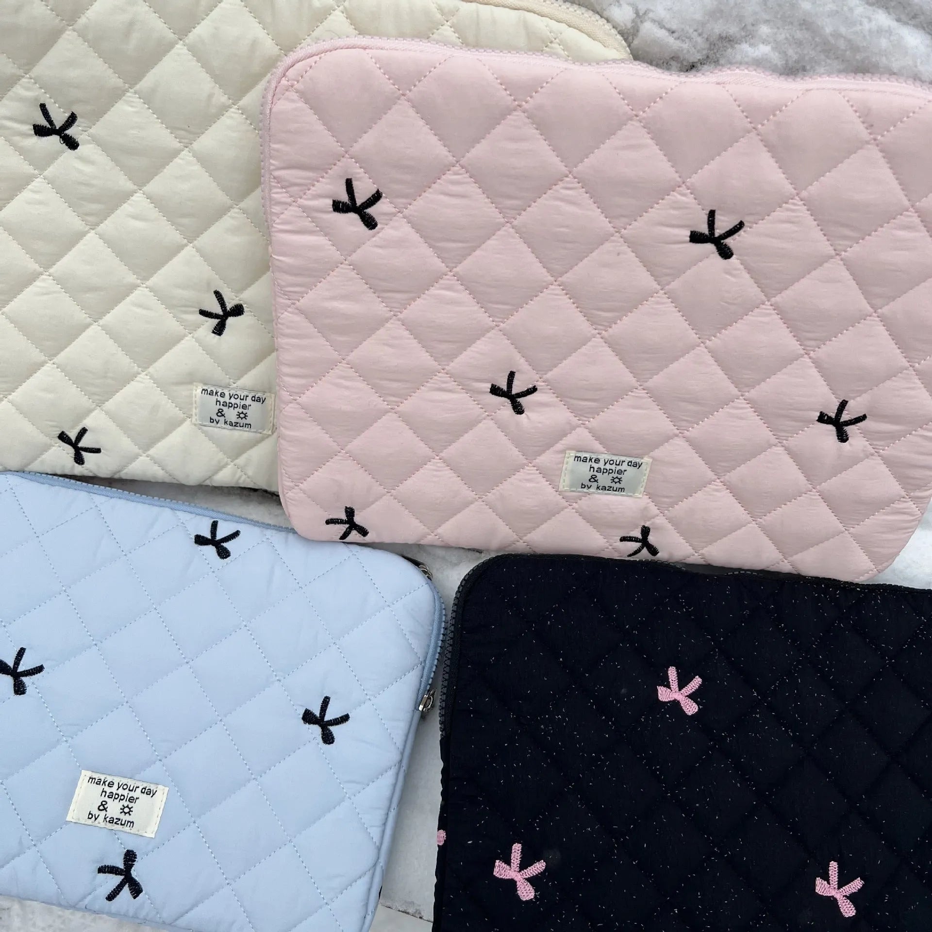 Nylon laptop storage bag with embroidered rhombus bow in light blue, showing size options.