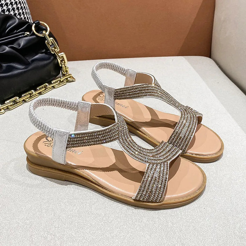 Women's patent leather sandals with rhinestone decoration on round toe shape, shown in gold colour
