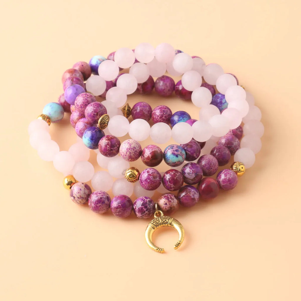Round pink Emperor Stone pendant on a silver-tone chain, laid flat.