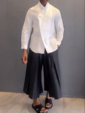 Women's white asymmetrical long sleeve shirt and black pleated trousers casual co-ordinates set on a hanger.