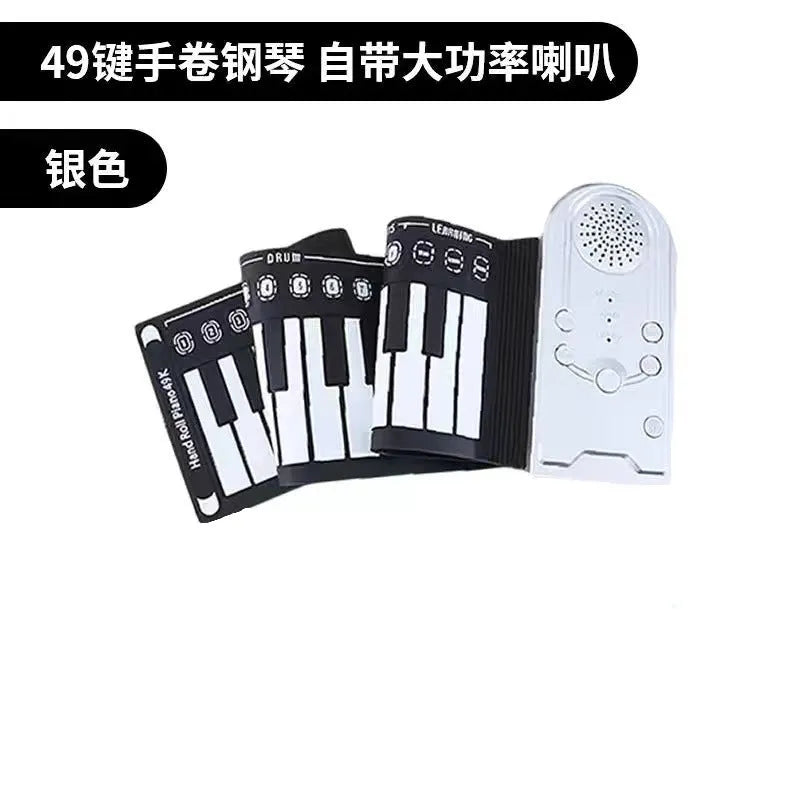 Rolled-up silicone keyboard next to black ABS control unit and speaker for portable 49-key electronic piano.